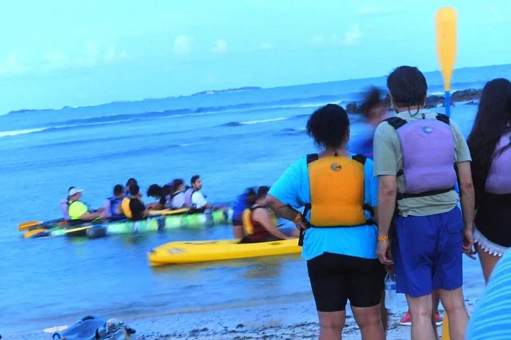 Personas subiendo a kayaks en la playa cerca del agua.